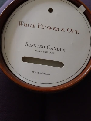 Doftljus White Flower & Oud - Säljer ett doftljus med doften White Flower & Oud. Ljuset kommer i en rund, brun keramikbehållare med dekoratim målning. Perfekt för att skapa mysig stämning hemma och sprida en fräsch doft i rummet. 5 vekar