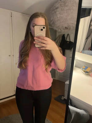 Rosa kortärmad topp i bomull - En söt rosa topp med korta ärmar och rund halsringning. Toppen har en avslappnad passform och är tillverkad i mjuk bomull, perfekt för en chill och trendig look.