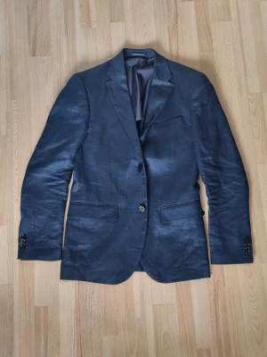 Mörkblå kostym - Snygg mörkblå kostym med klassisk kavaj och matchande byxor. Använd en gång, oklar storlek men modellen i bilden är 186 så utgå från det. Perfekt för skolavslutning.