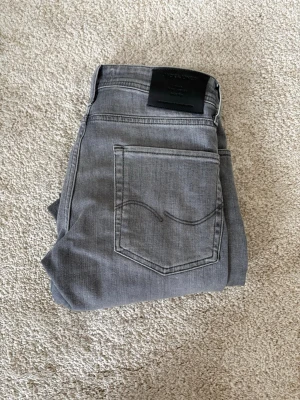 Grå jeans från jack&jones - Snygga grå jeans från Jack and Jones i model taperd fit och midja i 28 och längd i 30 perfekt för dig som gillar lite mer soft jeans. skriv gärna  vid funderingar