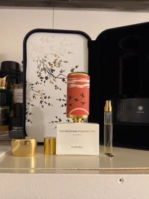 Floraïku The Mountain Standing Still edp parfym - Unisexparfym från Floraïku i en elegant vit flaska med guld- och röd dekorativ kork med fågelmotiv. Ingår gör även en mindre sprayflaska och exklusivt etui med blommönster. Lyxig och konstnärlig design som sticker ut i parfymhyllan.