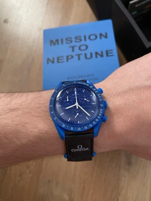 Omega x Swatch Mission to Neptune - Snygg blå Omega x Swatch Mission to Neptune klocka med svart armband och tydlig logga. Klockan har rund urtavla, kronograf och tachymeter. Tillverkad i biokeramik och levereras i originalbox.
