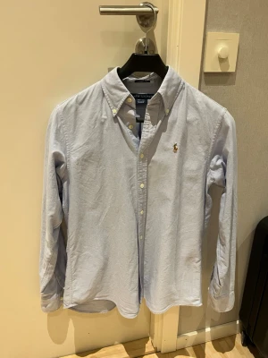 Ralph Lauren skjorta - Nyskick - Jag säljer en stilren Ralph Lauren skjorta med broderad logga på bröstet.🩵Skjortan har långa ärmar och vita knappar framtill. Passar både till vardags och lite finare tillfällen.💛Inköpspris: 1249 kr Mitt pris: 349 kr ✅ Bara hör av dig vid frågor och funderingar.😁(Fraktar samma dag vid köp 🙌)