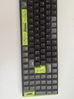 Iquinx f97 tangentbord  - Unikt mekaniskt tangentbord med svarta tangenter och detaljer i limegrönt. Tangenterna har specialtryck och grafik, vilket ger ett coolt och personligt utseende. Perfekt för gaming eller skrivbordssetup. Kompakt layout och modern design. Ny pris 2500kr
