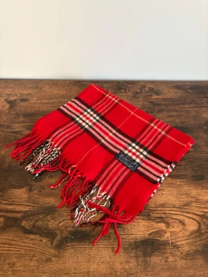 Burberry Halsduk - Vintage Burberrys halsduk i 100% lambswool. Made in England. Klassisk check i mörkare/bruna toner med diskret och tidlös look. Väldigt bra skick med endast mindre tecken på användning. Perfekt för en clean casual/old money stil.
