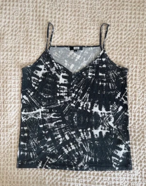 Vintage linnetopp - Snygg vintage linnetopp från Bik Bok i svart och vitt med abstrakt mönster. Toppen har smala axelband och v-ringning, perfekt för en trendig look. Materialet känns lätt och svalt, passar bra till jeans eller kjol.