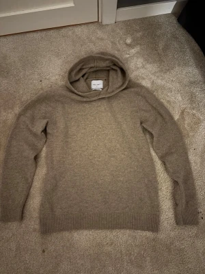 Beige hoodie i ull från Vailent! Storlek S  - Mysig beige hoodie från Wills i mjuk ullmix. Klassisk modell med huva, långa ärmar och ribbade muddar vid ärmslut och nederkant. Perfekt för en chill och stilren look. I storlek Small!