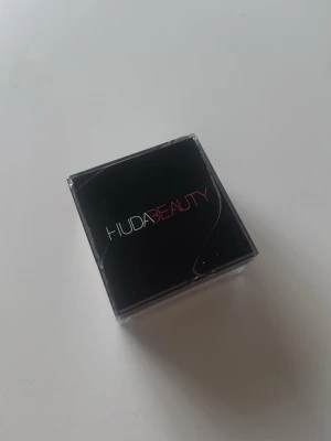 Huda beauty puder - Säljer min Huda puder, som ni ser på bilden har locket gått sönder och därav pris, sedan finns det ett litet håll i botten!!