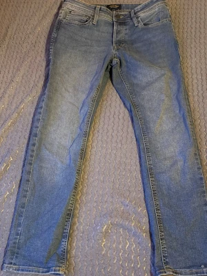 Blå slim jeans från Jack&Jones - Snygga blå slim jeans från Jack&Jones med klassisk femficksdesign och normal midja. Jeansen har en lätt tvättad look och smal passform hela vägen ner. Perfekta till en avslappnad stil och funkar året runt.”Aldrig använda”