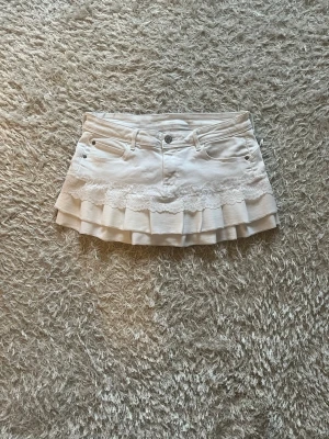 Vit volangkjol med spetsdetalj - En vit jeanskjol omsydd från ett par jeans. 🌷  Midjemått tvärsöver- ca 38cm  Längd - 29cm