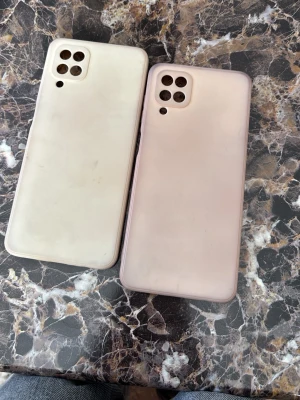 Två silikon mobilskal i beige och rosa Samsung A12 - Säljer två mjuka mobilskal i silikon, ett i beige och ett i ljusrosa. Båda har öppningar för fyra kameror och en blixt, och passar till Samsung Galaxy-modeller med fyrkantig kameramodul. Perfekt för dig som vill skydda mobilen med stil. Samsung A12