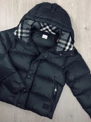 Svart pufferjacka från Burberry -  en Burberry vinterjacka i väldigt fint skick. Den är varm, bekväm och känns riktigt lyxig att ha på sig – perfekt nu under vintern. Klassisk och stilren modell som funkar till det mesta och aldrig går ur tiden.  Jackan är sparsamt använd och väl omhändertagen. En sån där jacka man bara tar på sig och känner sig snygg direkt.  ✨ Kan vara den perfekta Alla hjärtans dag-presenten till någon du tycker om (eller till dig själv 😉).  ✔️ Varm och fodrad ✔️ Mycket fint skick  💸 Pris går att diskuteras 