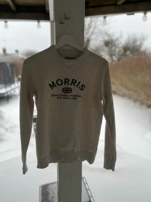 Morris Stockholm Travis Tröja – Storlek XS - Säljer en klassisk stickad tröja från Morris Stockholm i modellen "Travis". Fin ljusbeige färg med broderad logga på bröstet. • Storlek: XS • Skick: Mycket fint skick • Modell: Travis Oneck • Färg: Off-white / Beige. Hör av dig vid frågor 🙂🙂