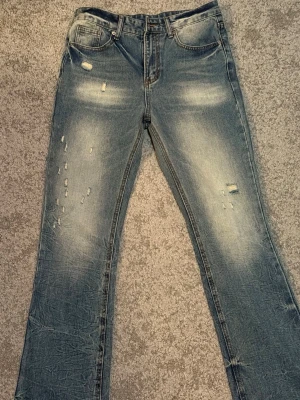 Ljusblå slitna jeans - Säljer ett par feta jeans med slitningar och distressed detaljer framtill. Jeansen har en straight/rak passform femficksmodell, ljus tvätt och markerade sömmar. Perfekta för en avslappnad och trendig look. Osäker vilket märke. 