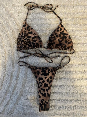 Leopardmönstrad bikini  - Trendig bikini med leopardmönster. Triangeltopp med knyt i nacke och rygg samt matchande trosa i stringmodell båda delarna i storlek XS ej använd bara testad 