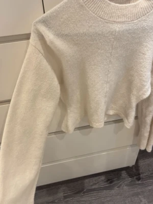 Gina stickad tröja - Vit/krämfärgad stickad tröja från Gina 14+ i storlek XXS, skulle säga att den passar en vanlig XS, långa breda ärmar och tajt i midjan, längst ner är det som en volang🥰 Endast använd 2 gånger!