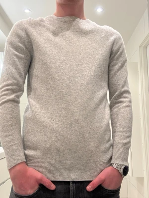 Ljusgrå Kashmir tröja - Säljer en stilren ljusgrå kashmir tröja. Tröjan har en klassisk passform och är perfekt för lager på lager. Materialet känns mjukt och bekvämt, den har ett litet slitage där av priset. skriv om det är någon fråga! Modellen är cirka 180 lång 