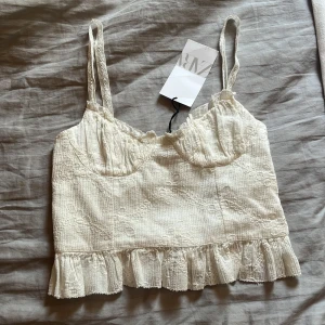 Vit broderad linnetopp från Zara - Supersöt vit linnetopp från Zara med tunna spetsband och broderade blommor. Toppen har volangkant nertill och lätt rynkade kupor. Super fin till sommaren! Helt ny endast provad men finns ej att köpa längre. Orginalpris 260 nok 