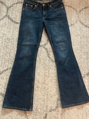 Mörkblå bootcut jeans - Säljer ett par mörkblå bootcut jeans med klassisk femficksdesign och snyggt utsvängda ben. Jeansen har normal passform och är tillverkade i ett mjukt bomullsmaterial. Perfekta för dig som gillar retrovibbar och vill ha ett par jeans som sticker ut.