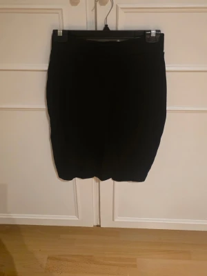 Svart tight kortkjol - En enkel och stilren svart kortkjol med tight passform. Få gånger använd. Har splitt baktill