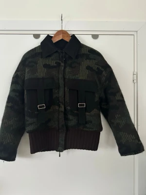 Carella bomber jacka, storlek S /M - Helt otroligt snygg kamouflagemönstrad / militärmönstrad jacka bomberjacka i storlek S/M. Mönsterstickat tyg med mudd nedtill och svarta detaljer på krage och fickor. Fina gulddetaljer på dragkedjan och bröstfickorna. Mycket fint skick!  Skickas mot porto, går även att hämta i Stockholm. 
