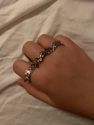 Snygg silverfärgad bladring - Unik ring i silverfärg med små bladformade detaljer som bildar ett elegant mönster runt fingret. Perfekt accessoar för dig som gillar naturinspirerade smycken och vill sticka ut med något annorlunda.