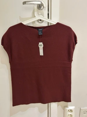  Ny Vinröd topp från Lindex - Vinröd topp från Lindex i enkel och stilren design. Toppen har korta ärmar och rak passform, tillverkad i mjukt material som känns skönt mot huden. Perfekt att matcha med jeans eller kjol för en clean look.