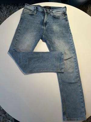 Ljusblå slim fit jeans från Replay - Säljer ett par ljusblå slim fit jeans från Replay med klassisk femficksdesign och dragkedjegylf. Jeansen har snygga slitningar och är tillverkade i mjuk denim med lite stretch för extra komfort. Perfekta till en avslappnad streetstyle-look. STORLEK 150-160cm höjd 