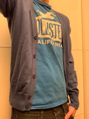 Mörkblå kofta med knappar från J.lindeberg  - Säljer en riktigt snygg stilren blå kofta från J.Lindeberg med knäppning framtill och långa ärmar. Klassisk passform och ribbade muddar vid ärmslut och nederkant. Vid funderingar, fråga på! 