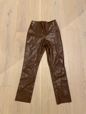 Byxor - Byxor i fin brun färg i storlek S. Dragkedja på sidan.