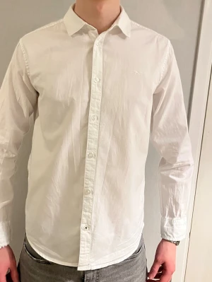 Vit skjorta från Hampton Republic - Klassisk vit skjorta från Hampton Republic med krage och knäppning framtill. Skjortan har lång ärm och en stilren, tidlös design som passar till många olika outfits. Tillverkad i bomull för en bekväm känsla.