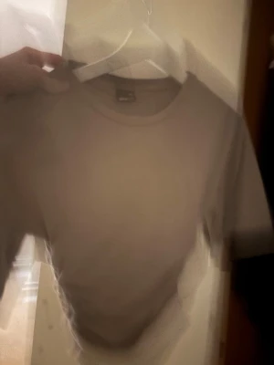 Klassisk vit t-shirt - En enkel och stilren vit t-shirt med rund hals och korta ärmar. Perfekt basplagg som passar till allt. Tillverkad i mjuk bomull för skön känsla hela dagen.