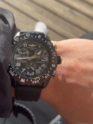 Svart Breitling Endurance Pro klocka - Säljer en sportig svart Breitling Endurance Pro klocka med robust boett och svart gummiband. Klockan har tydliga vita siffror, flera urtavlor och detaljer i gult. Perfekt för dig som gillar stilrena accessoarer med funktion.