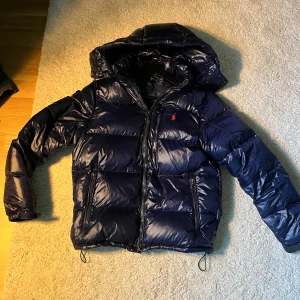 Mörkblå dunjacka från Polo Ralph Lauren - Snygg mörkblå dunjacka/vinterjacka från Polo Ralph Lauren  passar mellan 170-185 säljer pågrund av att börjar bli liten bara att höra av er vid frågor 