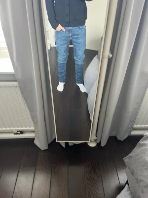 Nudie Jeans - Säljer ett par blå slim fit jeans med normal midja och klassisk femficksdesign. Jeansen har en snygg tvättad finish och kontrastsömmar. Perfekta till vardagsstilen och passar till det mesta. Materialet är troligtvis bomull med lite stretch för extra komfort.