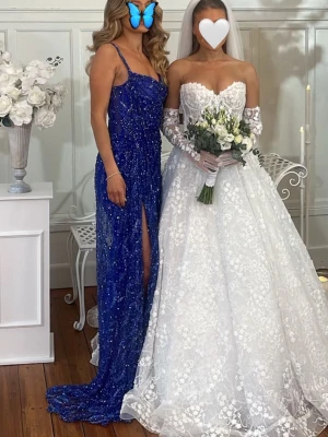 Blå glittrig långklänning med slits - Säljer en blå glittrig långklänning med smala axelband och hög slits framtill. Klänningen har figurnära passform och är täckt av paljetter som ger en snygg lyster. Perfekt för dig som vill sticka ut på bal eller fest.