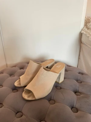 Beige slip-in klackar - Snygga beige slip-in klackar från XIT by Din Sko med öppen tå och bred klack. Perfekta för dig som vill ha en skön och unik klack till jeans, vardags eller varför inte fest. Liten defekt fläck på ena skon, se bild! 