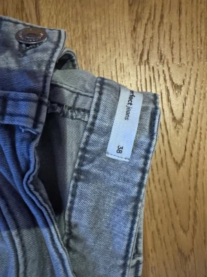 Ljusgrå jeans från Perfect Jeans - Säljer ett par ljusgrå jeans från Perfect Jeans i storlek 38. Klassisk femficksmodell med raka ben och normal midja. Jeansen är tillverkade i mjuk bomull och har en snygg, avslappnad passform som passar till det mesta.
