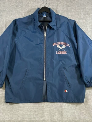 Champion USA Vintage Coaches Jacket Oversized XL Navy - Vintage Champion USA coaches jacket w/ Williamsville Lacrosse print (New York 🇺🇸). Clean navy nylon, heavy YKK zip + hidden hood in collar. Proper boxy oversized fit.  Tagged Size L fits XL oversized P2P 79 cm / Length 76 cm / Sleeve (collar) 91.5 cm  Good vintage condition, small marks shown but not noticeable worn.