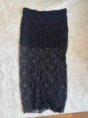 Svart spetskjol från Divided - Säljer en lång svart kjol från Divided i genomskinlig spets. Kjolen har en rak passform och är perfekt för dig som gillar en edgy och trendig stil. Materialet är lätt och luftigt, vilket gör den skön att bära under varmare dagar. Som ni ser på tredje bilden har den som slags trådar över hela kjolen men tror det kan gå bort💕
