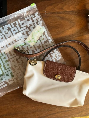 Longchamp mini väska beige - Så fin beige Longchamp väska, perfekt storlek och passar med vilken outfit som helst. I nyskick aldrig använd 