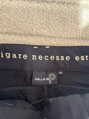 Mörkblåa shorts från Pelle P med bälte - Mörkblåa shorts från pelle P med praktiska fickor, snygga detaljer och medföljande bälte. Shortsen har broderad logga på benet och är perfekta för en aktiv livsstil. Materialet känns slitstarkt och passar bra till sommarens äventyr.