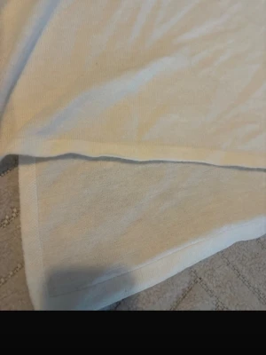 Vit kjol med knappar i bomull - Stilren vit kjol i mjukt bomullstyg med dekorativa knappar längs sidan. Kjolen har en enkel och rak form som gör den lätt att matcha med olika toppar. Perfekt för dig som gillar minimalistisk stil och ljusa färger.