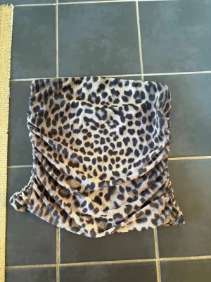 Leopardmönstrad linne i sammet - Coolt linnemed leopardmönster i mjuk sammet. Linnet har rynkade detaljer på sidorna som ger en snygg draperad effekt. Perfekt för dig som vill sticka ut med en trendig och djurinspirerad look.