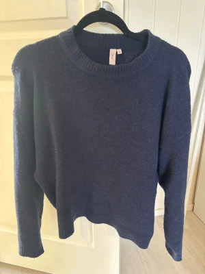 Mörkblå stickad tröja från nelly - En enkel och stilren mörkblå stickad tröja från Nelly med rund halsringning och långa ärmar. Tröjan har ribbstickade muddar vid hals, ärmslut och nederkant. 