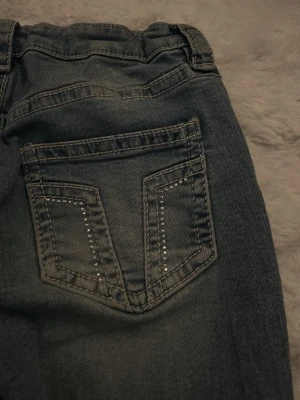 Blå bootcut jeans från Gina Young med glitter detaljer  - Säljer ett par blå bootcut jeans från Gina med snygga sömmar och små silvriga palletter på bakfickorna. Jeansen har klassisk femficksdesign och är tillverkade i denim. Perfekta för dig som gillar en avslappnad stil. Jeansen är som helt nya, har bara använt dem 1 gång. Men de är verkligen jättefina🥰