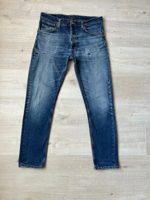 Blåa Nudie Jeans Lean Dean Storlek W34 L32 - Fina Nudie Jeans i blå färg. Jeansen är i mycket bra skick och sparsamt använda. |  Äkta som allt annat jag säljer! ✅ |  Storlek: W34 L32 | Skick: Mycket Bra Skick - en innerficka tejpad pga hål,  (SE SISTA BILD) | Färg: Blå | Märke: Nudie | Modell: Jeans |   Hör gärna av dig vid frågor så svarar jag så fort jag kan! 😁 |  (SKU - 105)