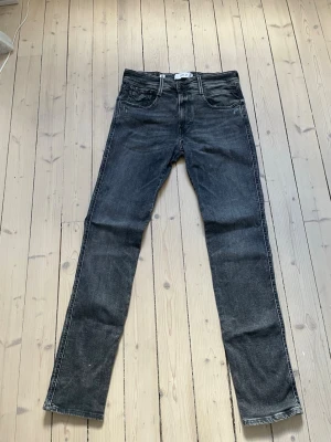 Svarta jeans från Replay - Säljer ett par svarta jeans från Replay med klassisk femficksmodell och raka ben. Jeansen har en snygg tvättad look och detaljerade sömmar på bakfickorna. Tillverkade i mjuk denim som sitter skönt hela dagen.