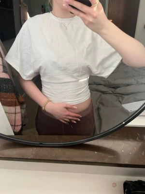 T-shirt från Nelly  - Snygg vit T-shirt från Nelly, lösare upptill och tajt i midjan. Tröjan är i en S men den passar som en XS. Sprillans ny har bara inte kommit till andvändning så mycket! Skriv vid frågor och funderingar💕