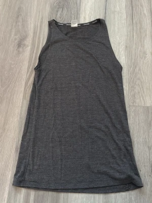 Mörkgrå linne från Calvin Klein - Mörkgrått linne från Calvin Klein i mjukt och stretchigt material. Perfekt för chill dagar hemma eller som loungewear. Klassisk design med logga längs insidan av halsringningen. Skön passform och lätt tyg.